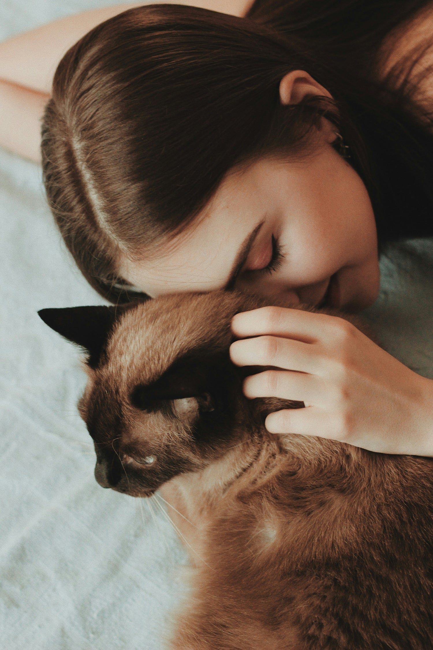 Eine junge Frau schmust mit ihrer Katze und lächelt